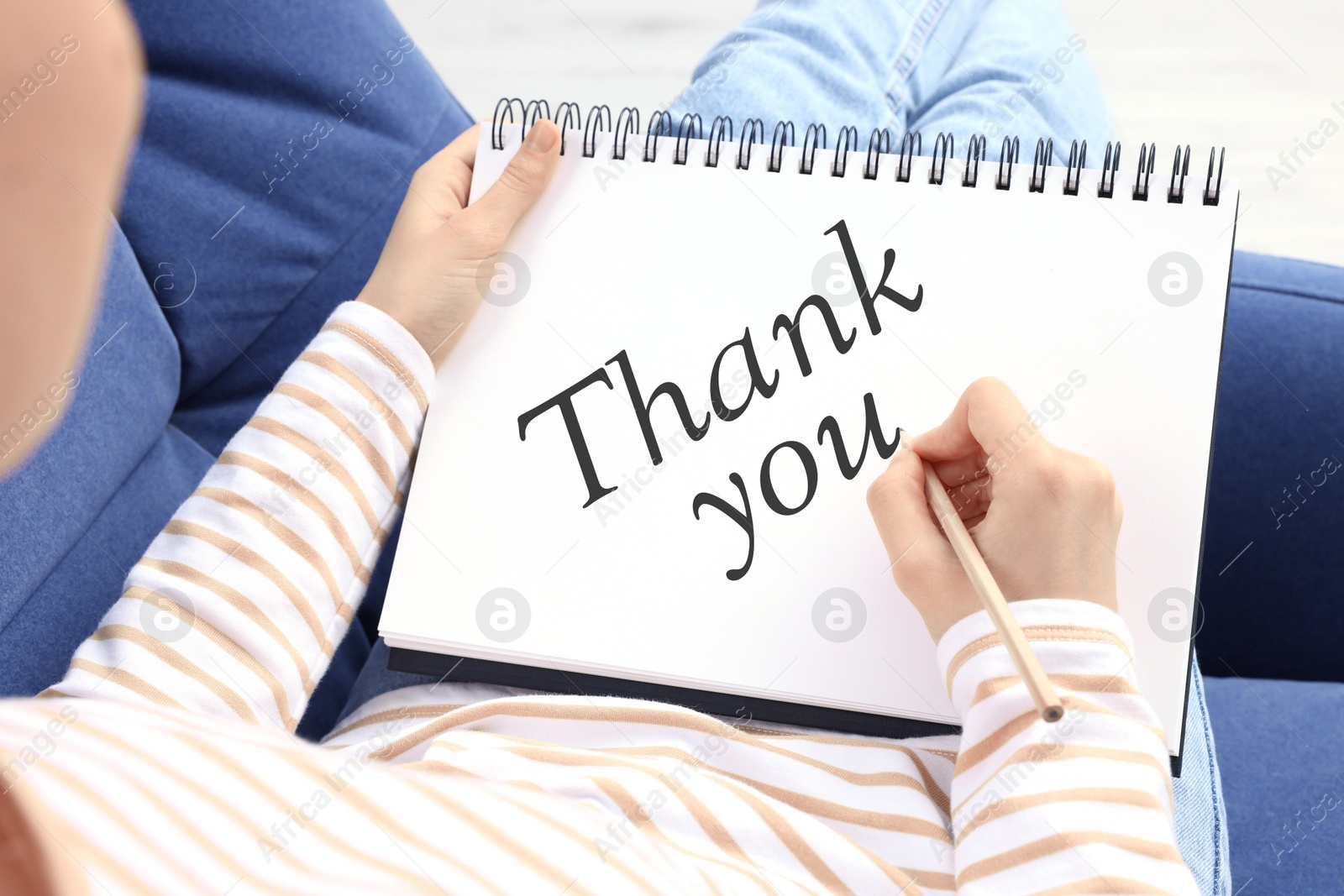 Image of Woman writing phrase Thank You in notebook at home, closeup