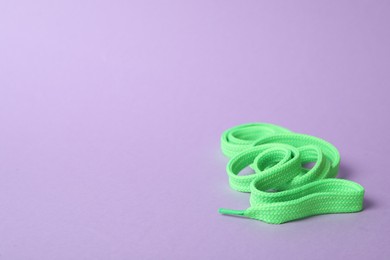 Photo of Mint shoe lace on lilac background. Space for text