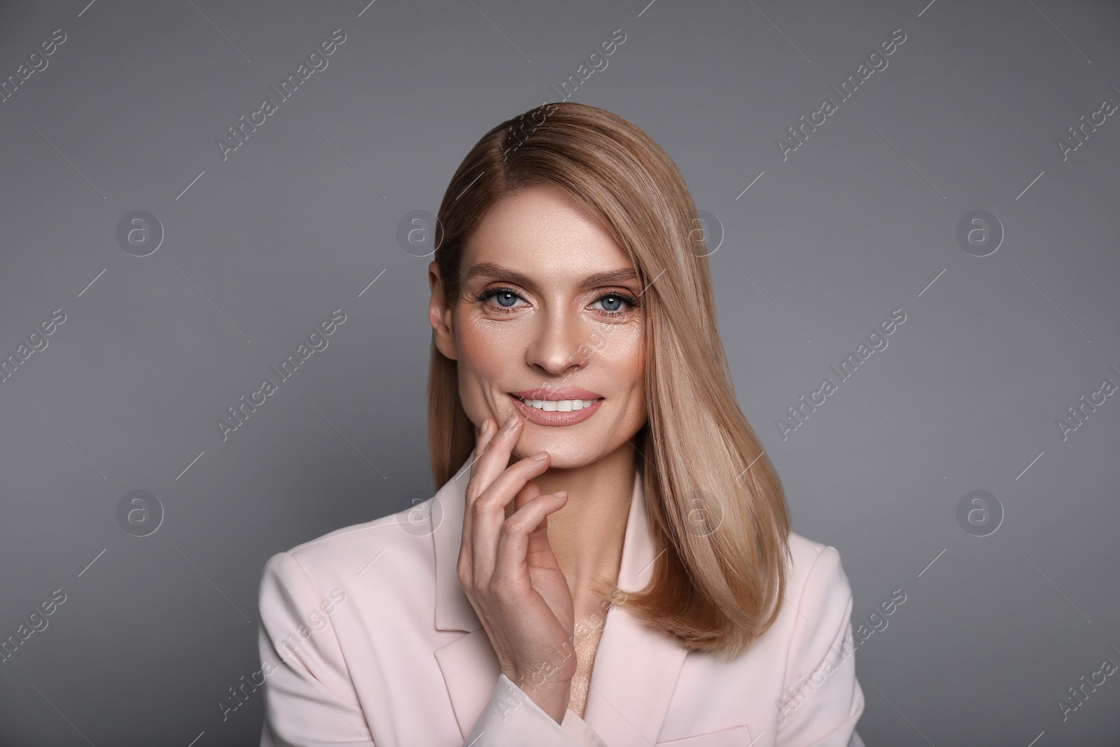 Image of Portrait of stylish attractive woman with blonde hair on grey background
