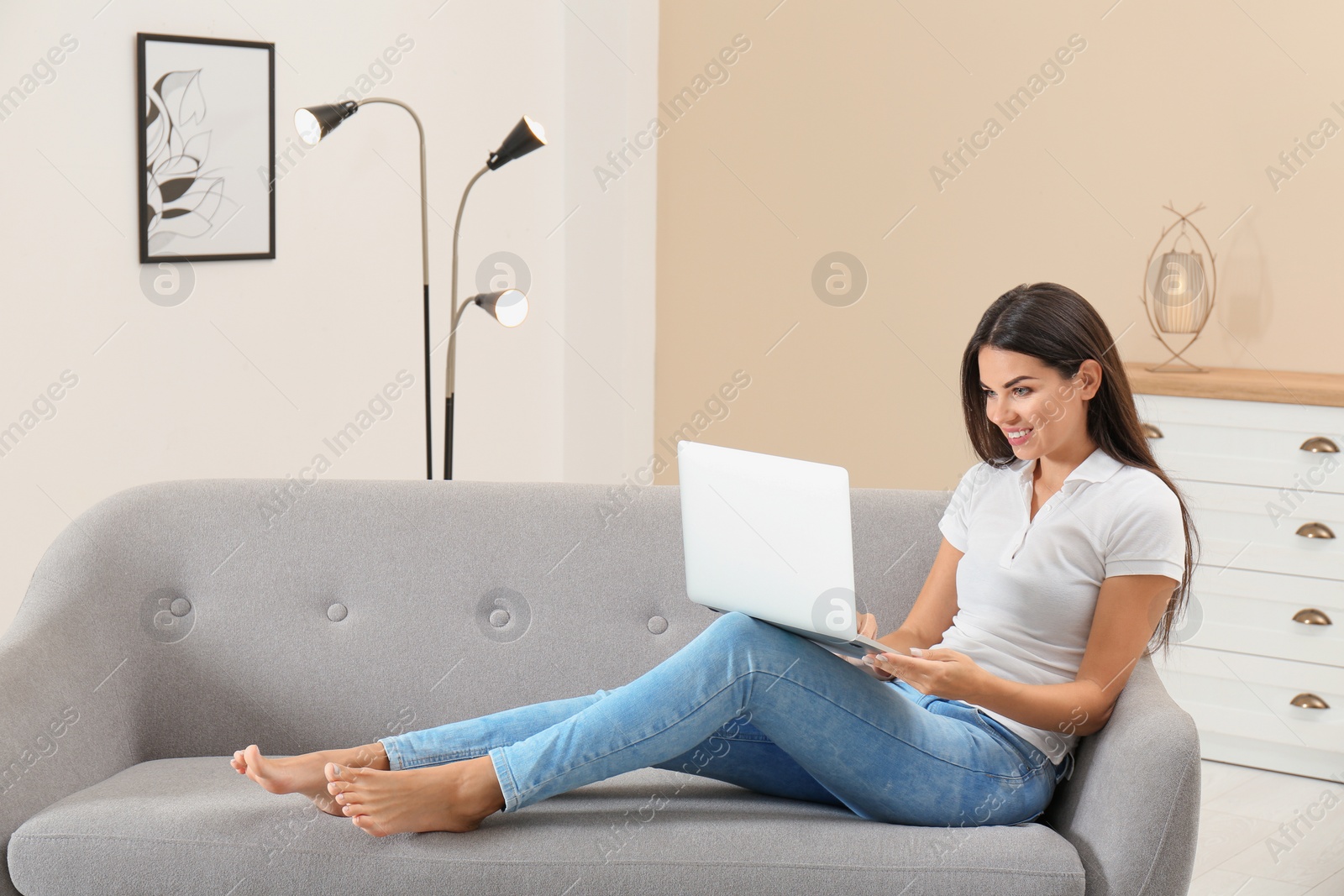 Photo of Beautiful woman with laptop sitting on sofa at home