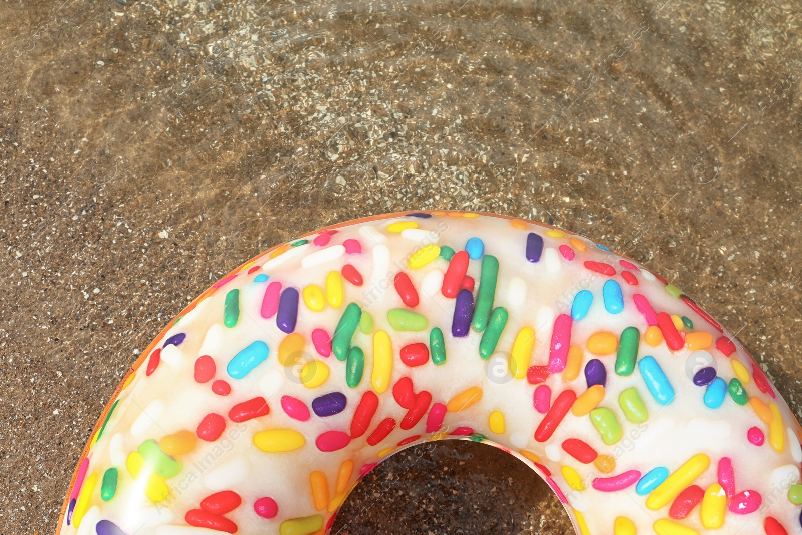 Photo of Bright inflatable doughnut ring floating on sea water, top view. Space for text