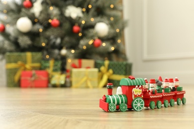 Bright toy train on floor in room with Christmas tree