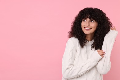 Happy young woman in stylish white sweater on pink background, space for text