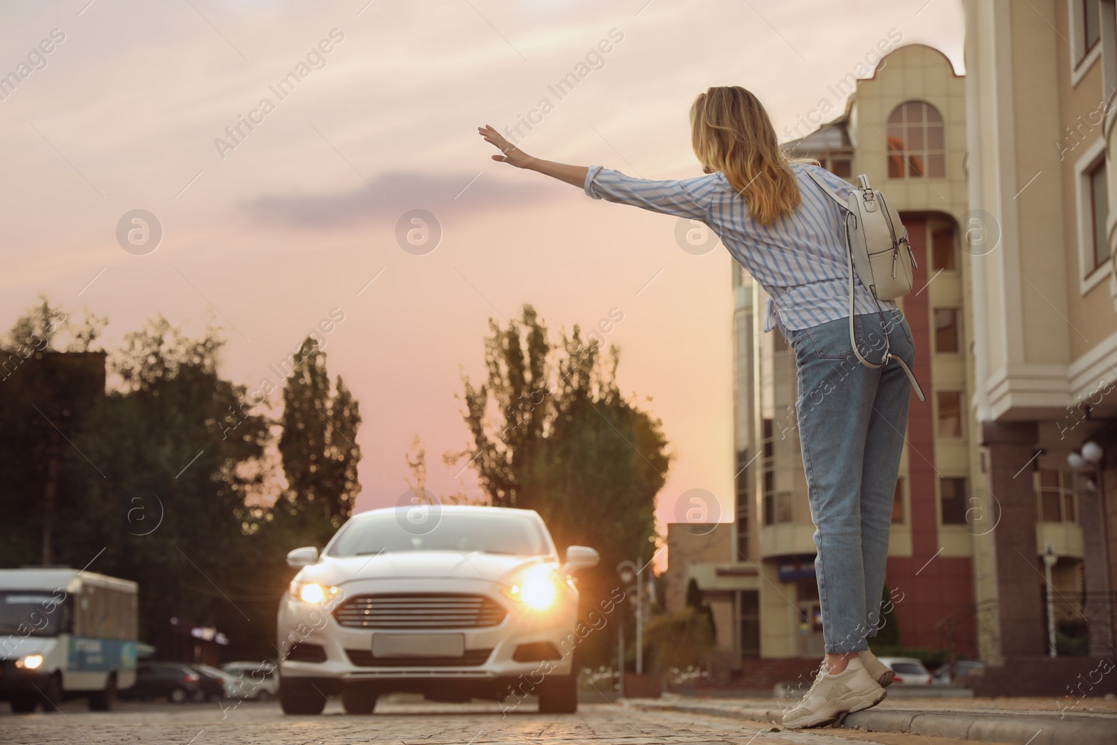 Photo of Young woman catching taxi on city street