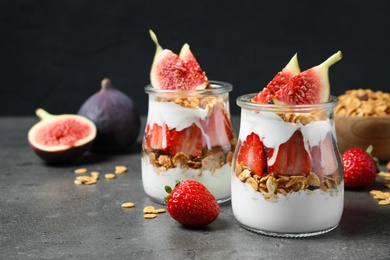 Photo of Jars of tasty homemade granola dessert on grey table. Healthy breakfast