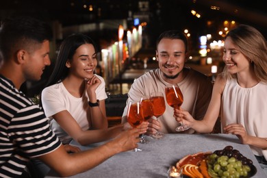Photo of Friends with glasses of cocktails spending time together on roof cafe terrace at night