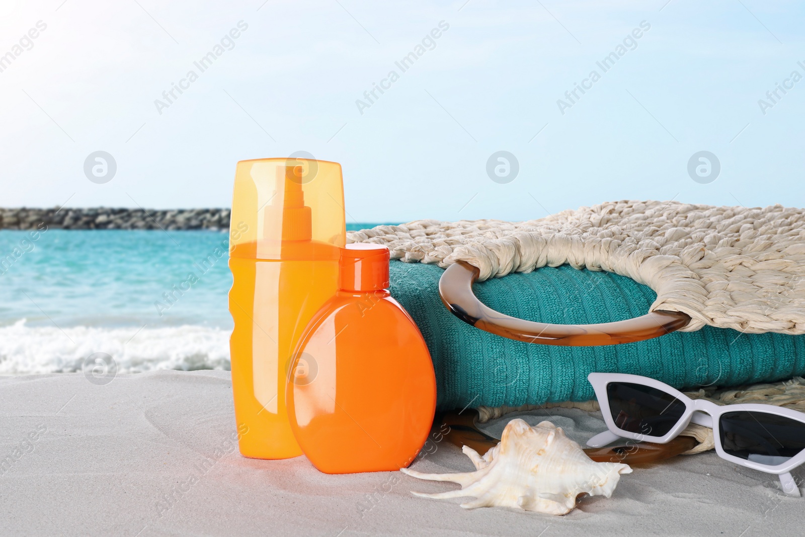 Image of Set of sun protection products and stylish accessories on sandy beach