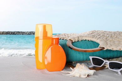 Image of Set of sun protection products and stylish accessories on sandy beach