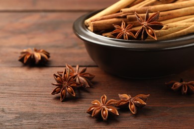 Photo of Bowl with cinnamon sticks and star anise on wooden table, closeup