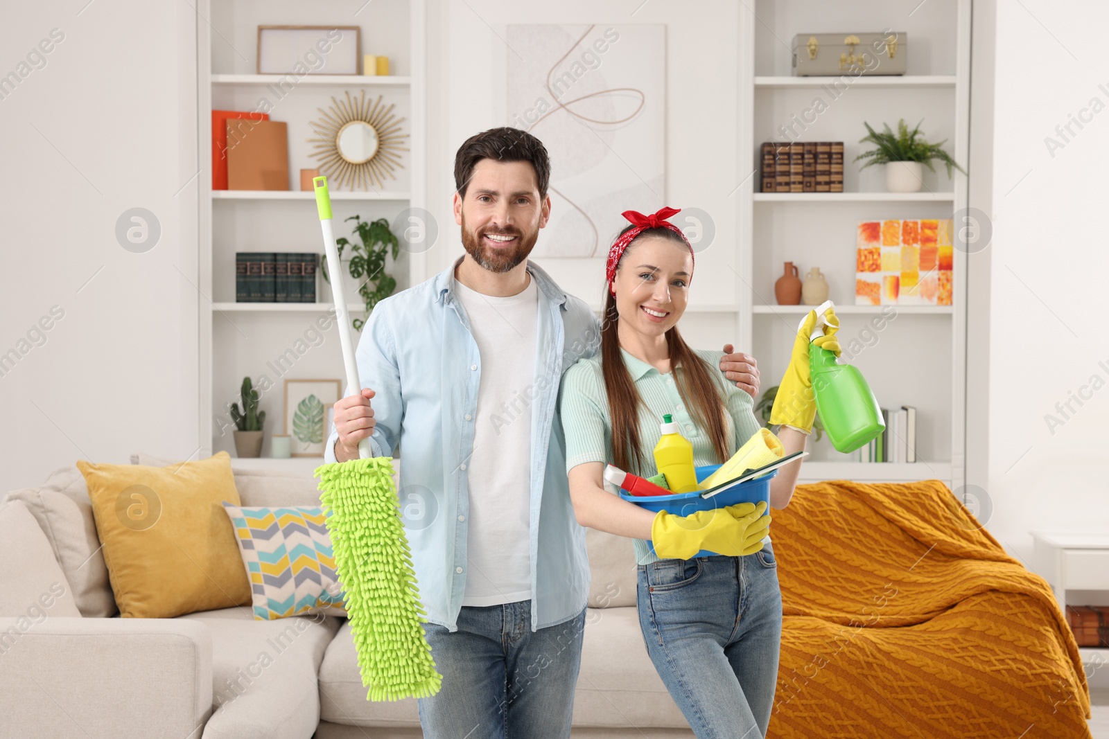 Photo of Spring cleaning. Couple with detergents and mop in living room