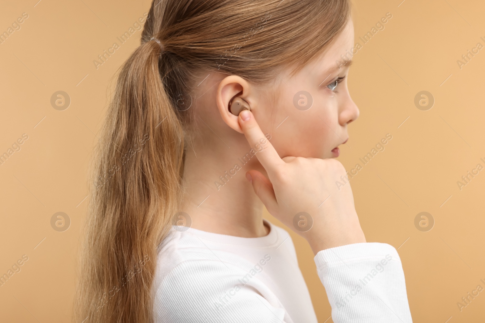 Photo of Little girl with hearing aid on pale brown background