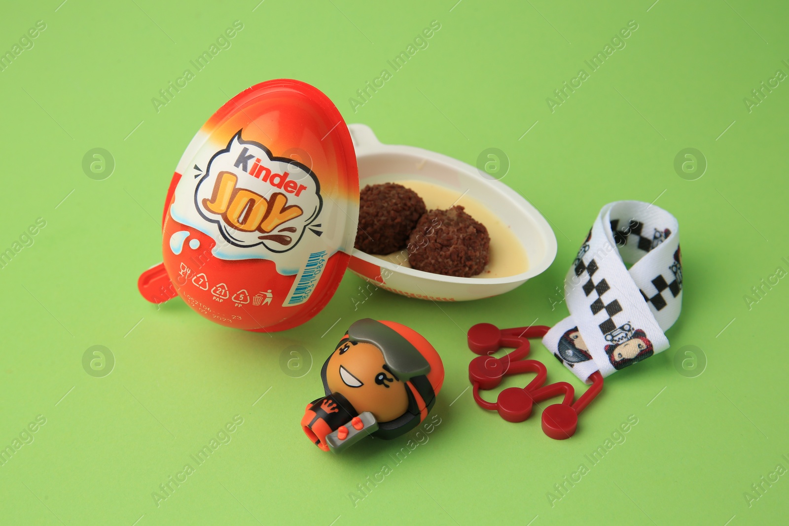 Photo of Sveti Vlas, Bulgaria - June 29, 2023: Halves of Kinder Joy Egg with sweet candies and toys on light green background