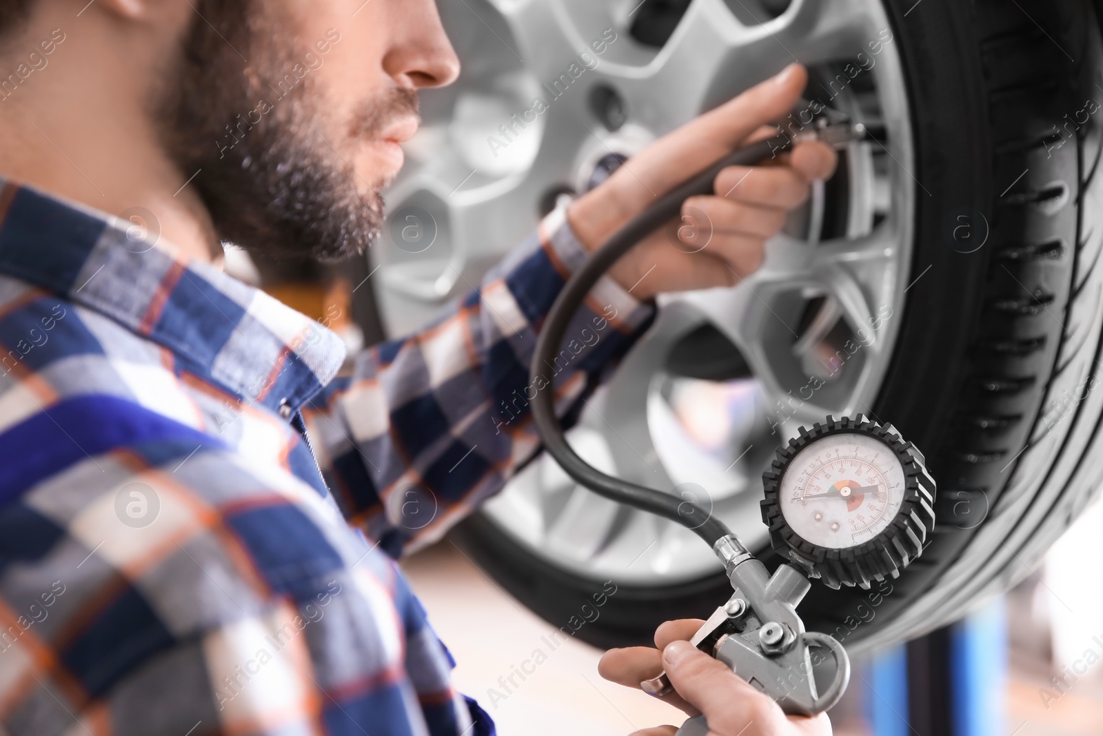 Photo of Mechanic checking tire pressure in service center, closeup