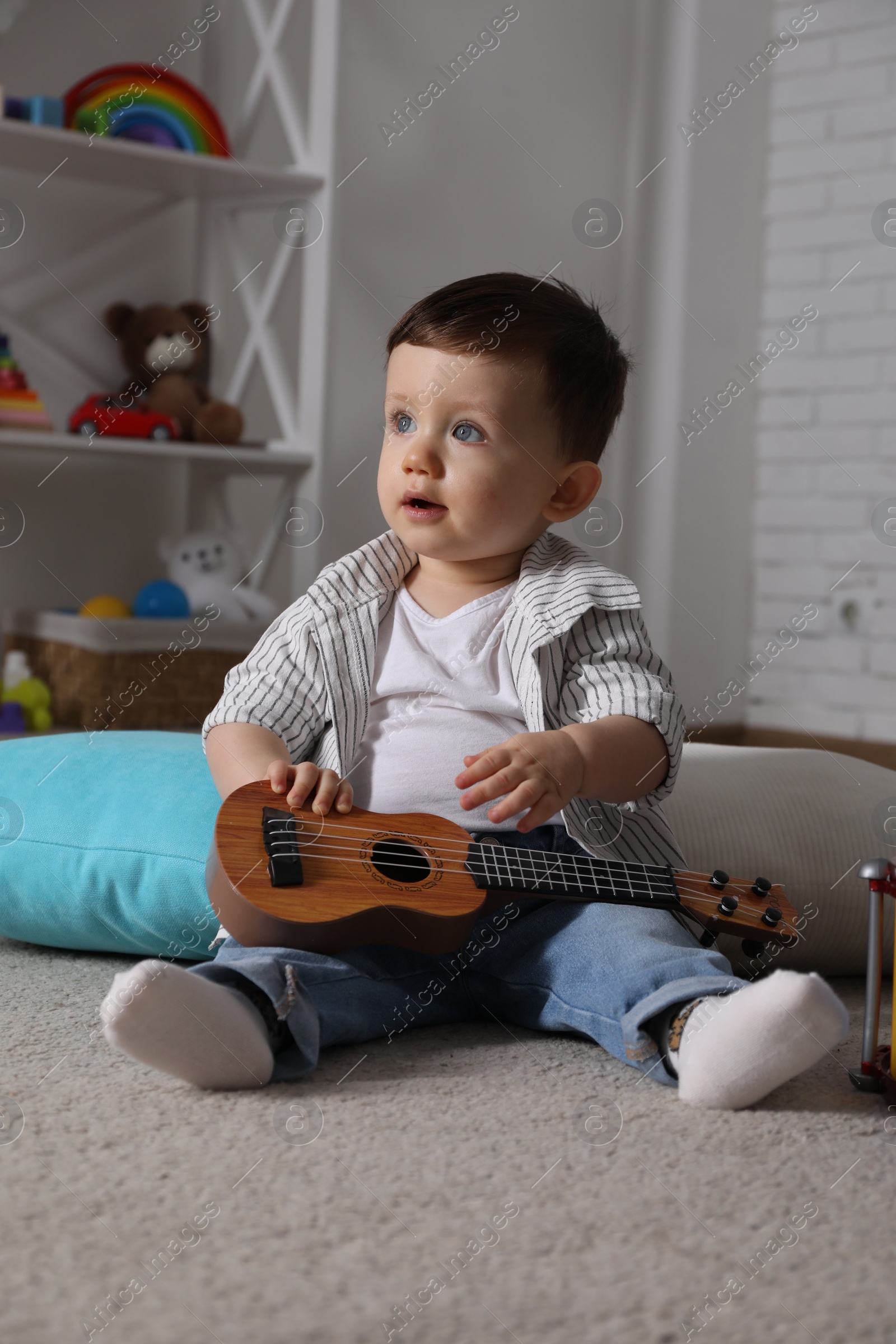 Photo of Cute little boy with toy guitar at home