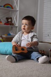 Cute little boy with toy guitar at home