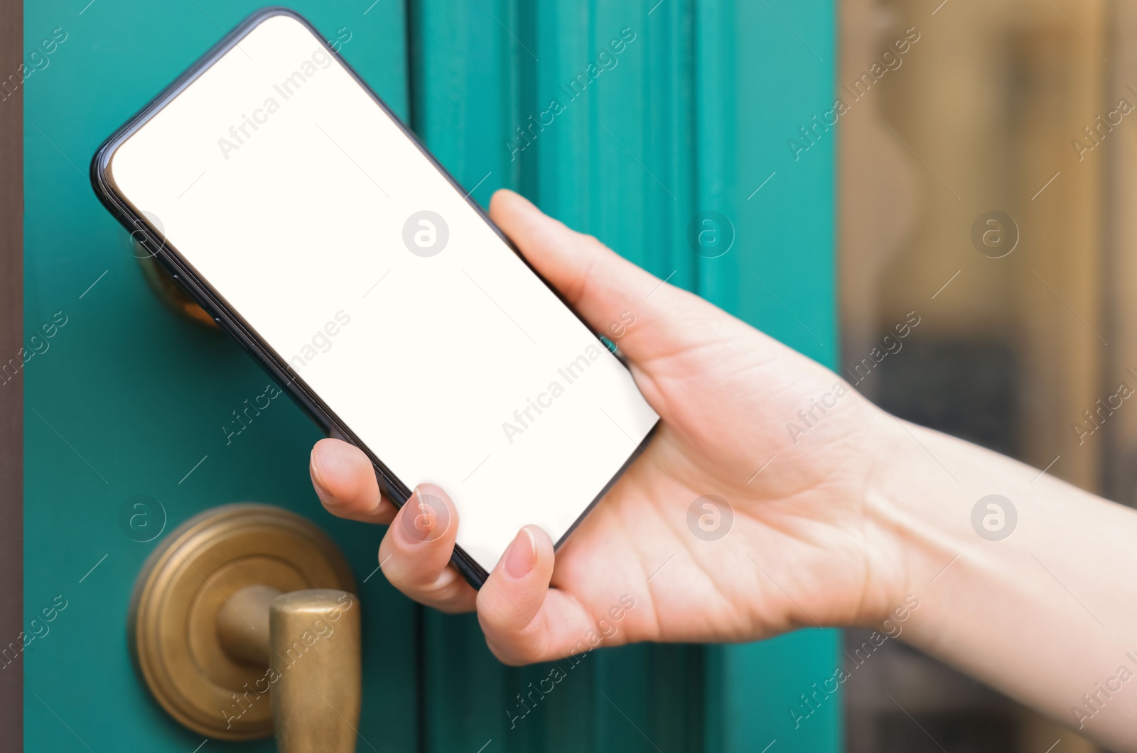 Photo of Woman opening door with smartphone outdoors, closeup