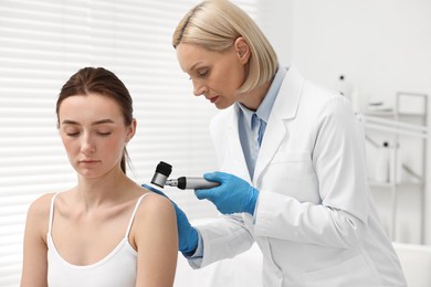 Dermatologist with dermatoscope examining patient in clinic