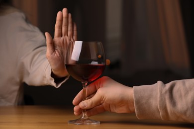 Photo of Woman refusing to drink red wine indoors, closeup. Alcohol addiction treatment