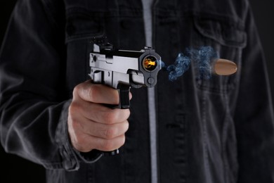 Image of Man shooting from gun on black background, closeup