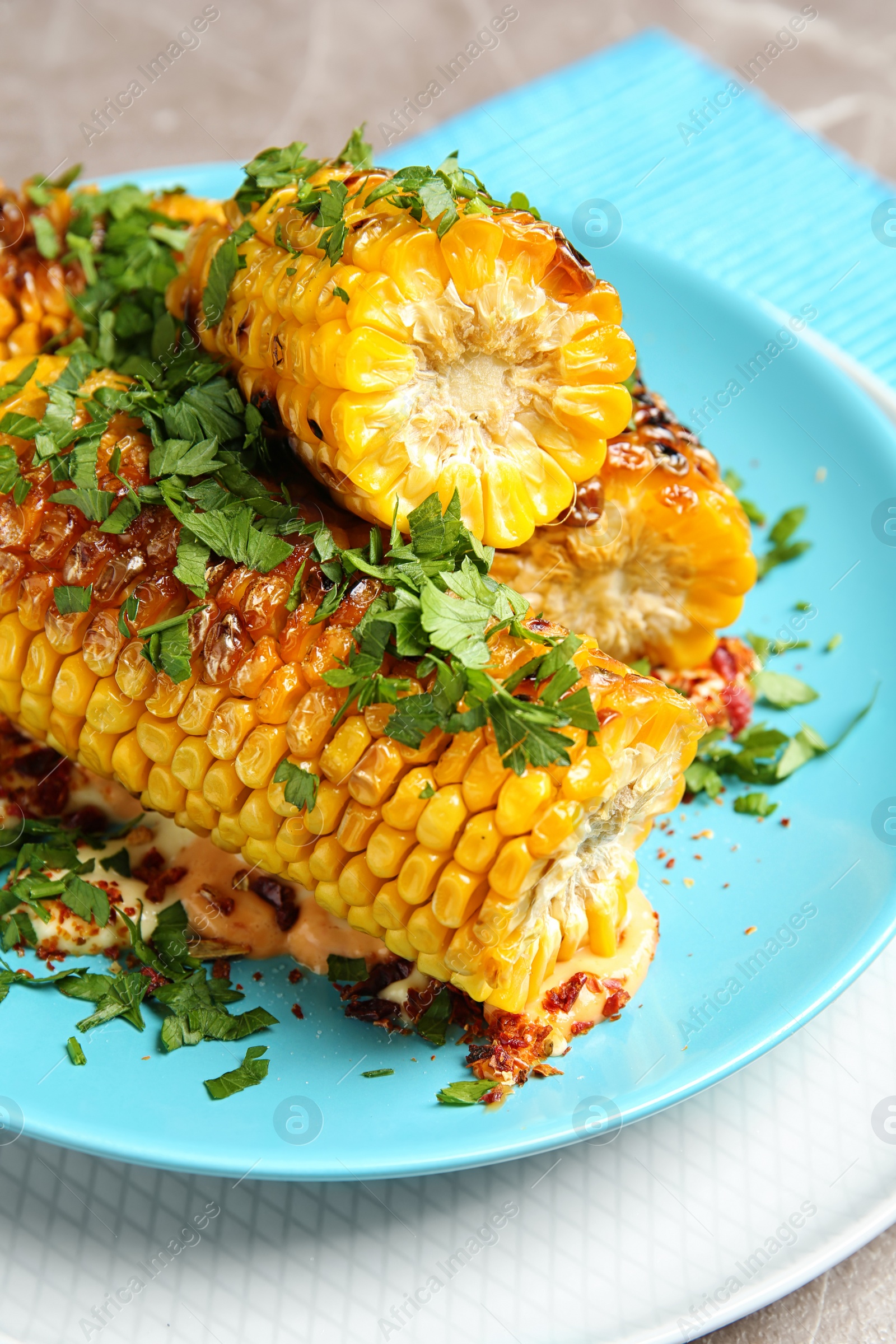 Photo of Plate with delicious grilled corn cobs and parsley on table, closeup