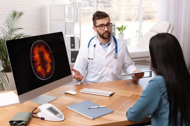Photo of Neurologist consulting young patient at table in clinic