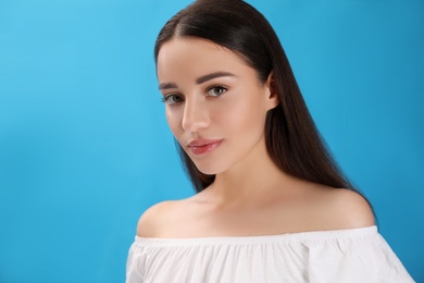 Portrait of beautiful young woman on light blue background