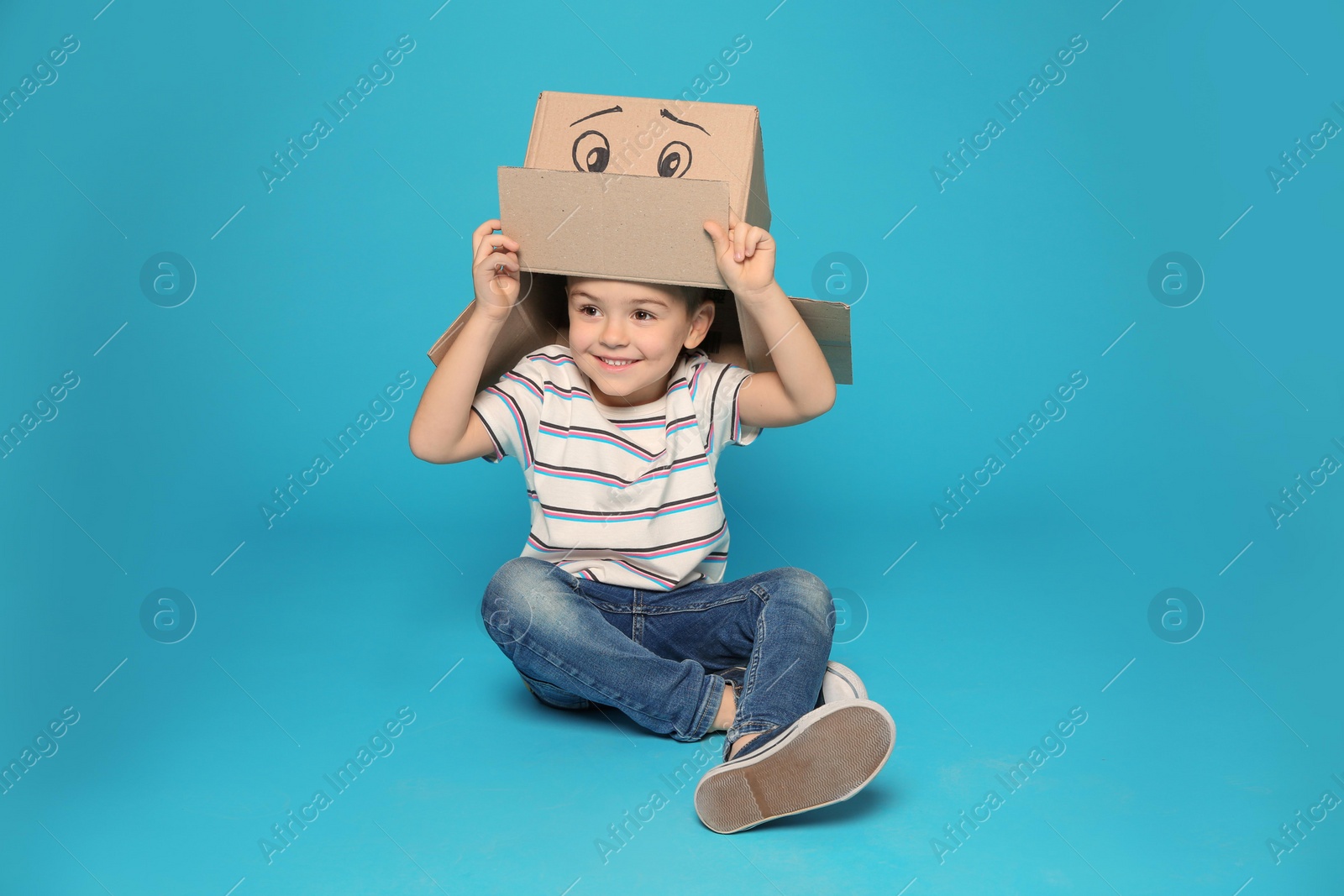 Photo of Cute little boy holding cardboard box with smiling face on color background