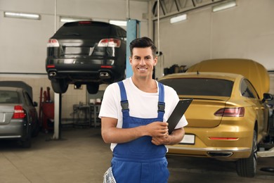 Portrait of professional mechanic with clipboard at automobile repair shop