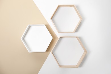 Photo of Empty honeycomb shaped shelves on color wall