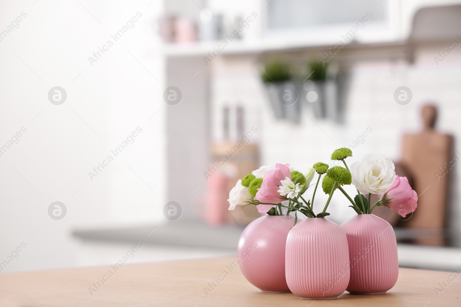 Photo of Vases with beautiful flowers on table in kitchen interior. Space for text