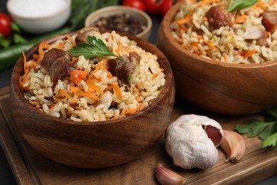 Delicious pilaf with meat and carrot in bowls on table, closeup