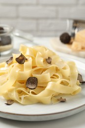 Photo of Delicious pasta with truffle slices served on white table, closeup