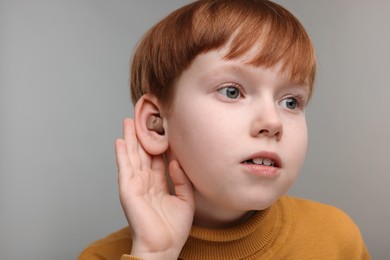 Photo of Little boy with hearing aid on grey background