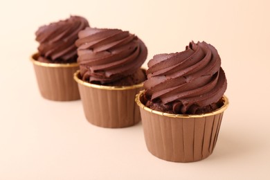 Photo of Delicious chocolate cupcakes on beige background, closeup