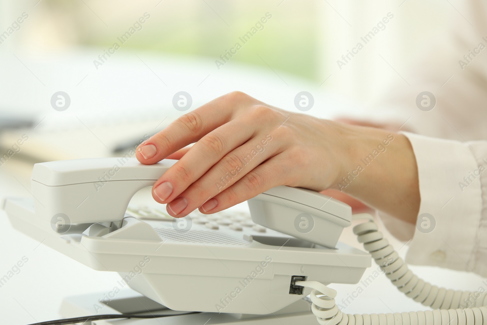 Photo of Assistant taking telephone handset on blurred background, closeup