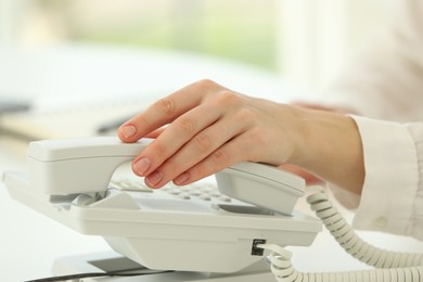 Assistant taking telephone handset on blurred background, closeup