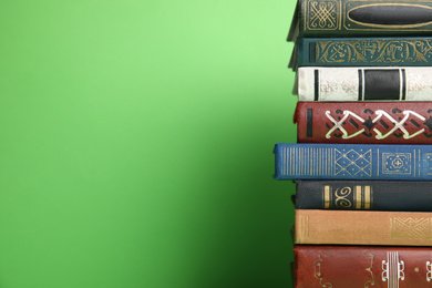 Photo of Stack of hardcover books on green background. Space for text