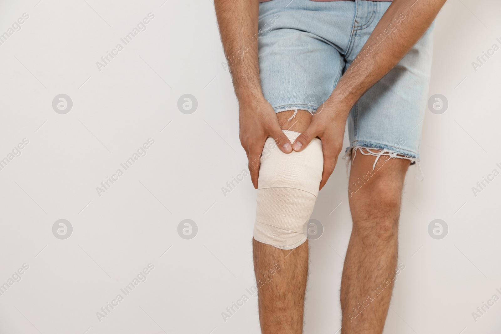 Photo of Man with bandage on his knee against light background, closeup. Space for text