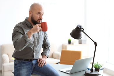 Portrait of confident young man drinking coffee in room