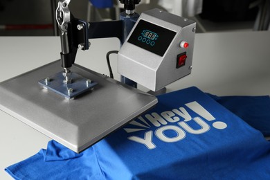Photo of Printing logo. Heat press with blue t-shirt on white table, closeup