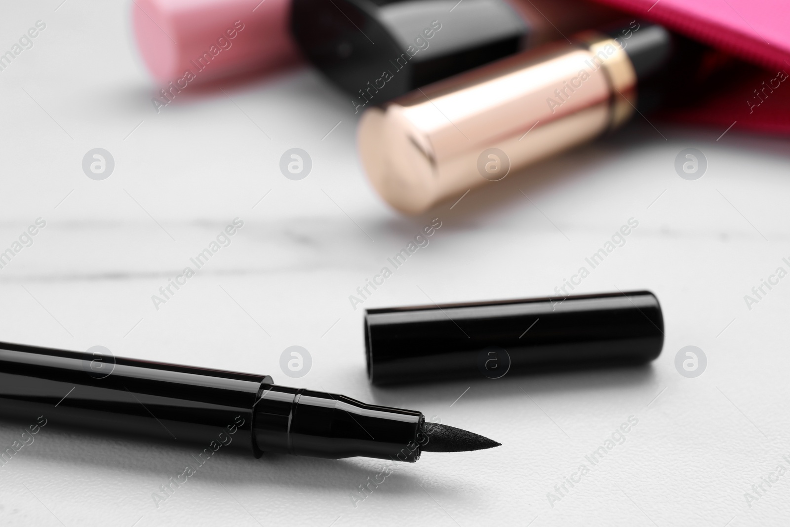 Photo of Black eyeliner on white marble table, closeup. Makeup product