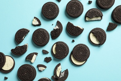 Tasty chocolate cookies with cream on color background, flat lay