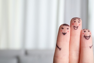 Photo of Three fingers with drawings of happy faces on blurred background, space for text