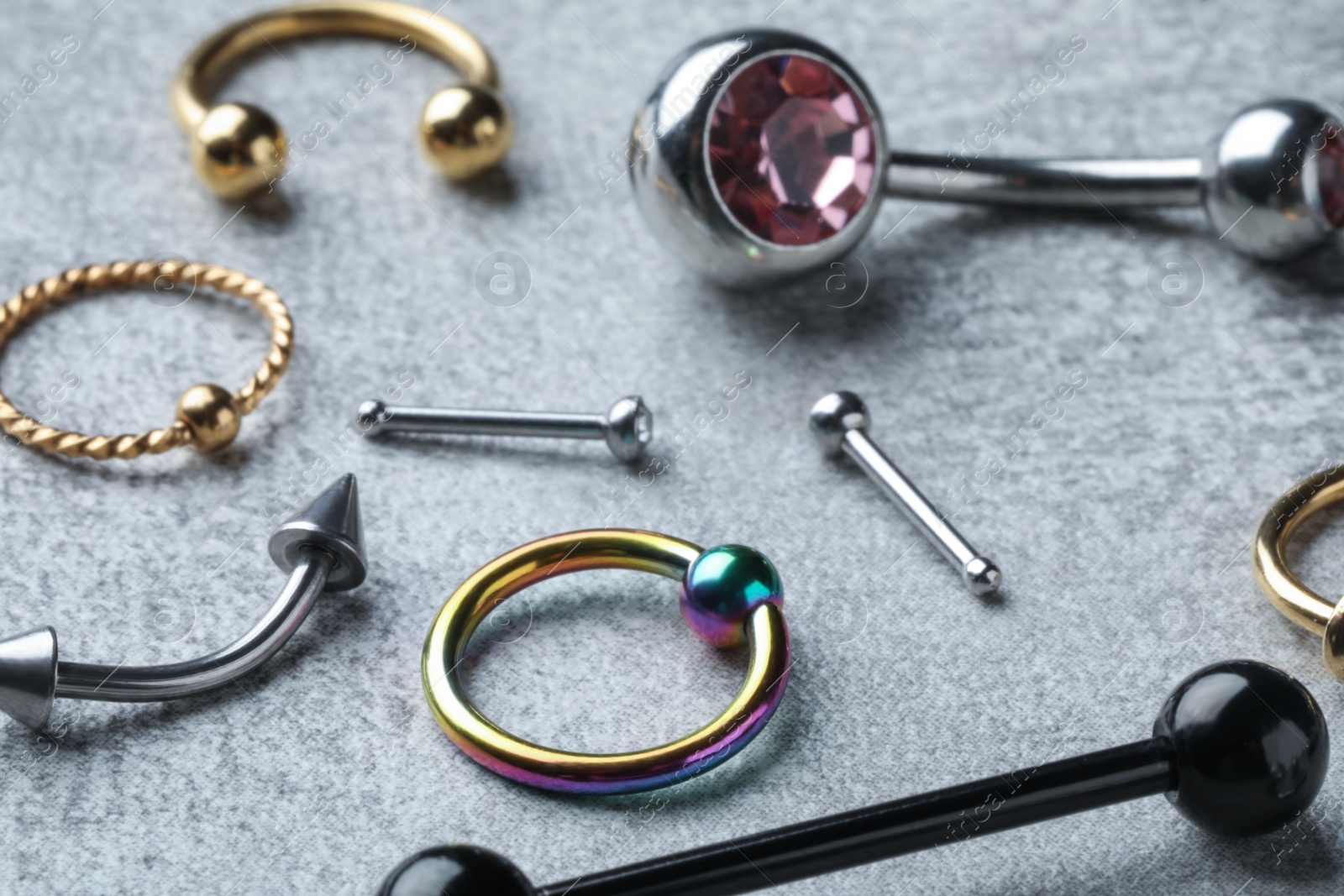 Photo of Stylish piercing jewelry on light grey table, closeup