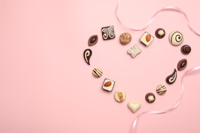 Photo of Heart made with delicious chocolate candies on light pink background, flat lay. Space for text
