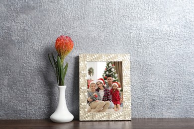 Image of Christmas portrait of family in photo frame on table near grey wall