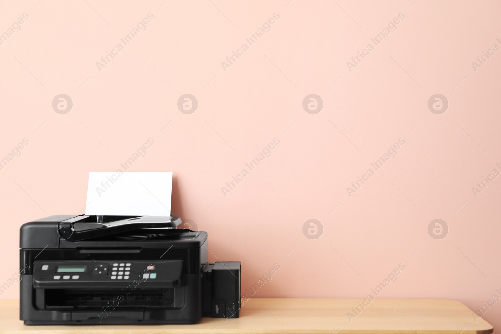 Photo of Modern printer with paper on wooden table. Space for text