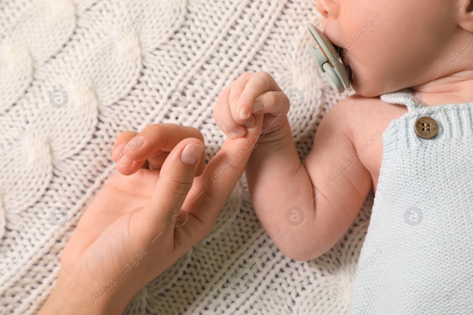 Photo of Mother and her newborn baby on white knitted plaid, top view