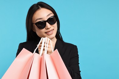 Photo of Smiling woman with shopping bags on light blue background. Space for text