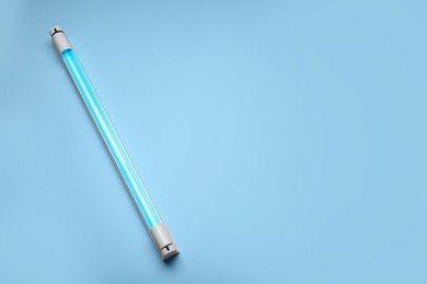 Photo of Ultraviolet lamp on light blue background, top view. Space for text